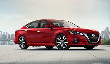 2023 Nissan Altima in red with city in background illustrating last year's 2022 model in Greeley Nissan in Greeley CO
